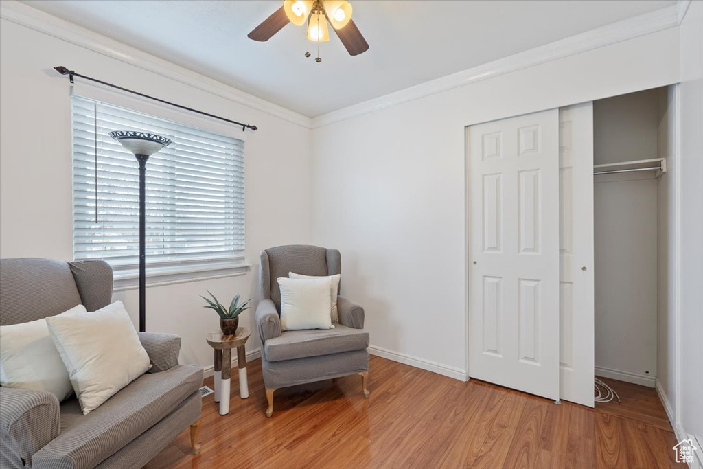 Living area featuring ornamental molding, baseboards, a ceiling fan, and light wood-style floors