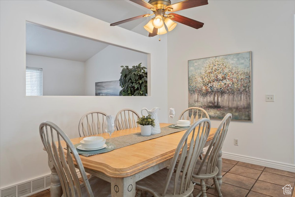 Dining space featuring ceiling fan, tile patterned flooring, vaulted ceiling, visible vents, and baseboards