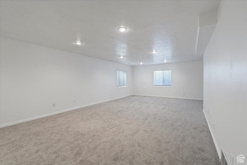 Carpeted empty room with visible vents, baseboards, and recessed lighting