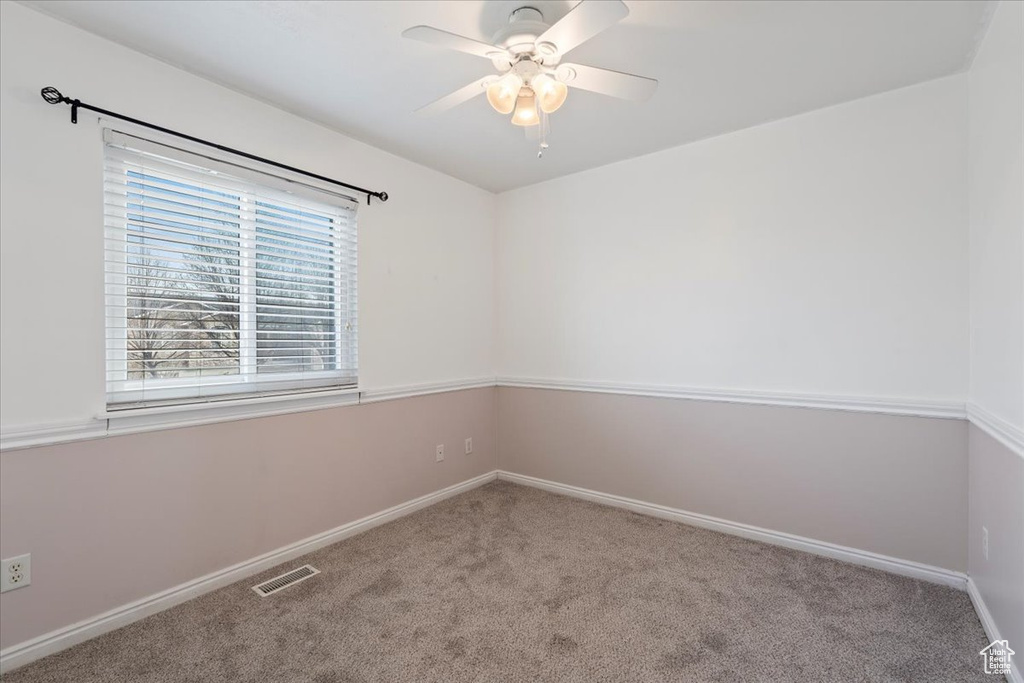 Carpeted empty room featuring visible vents, baseboards, and ceiling fan