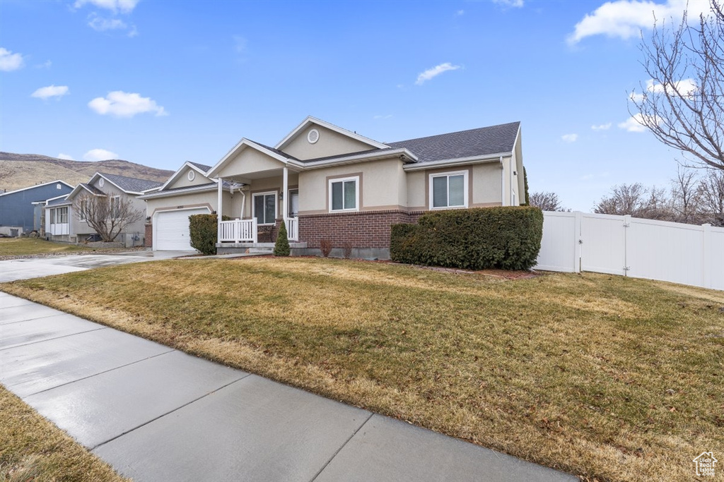 Ranch-style home featuring a front yard, fence, stucco siding, brick siding, and a gate