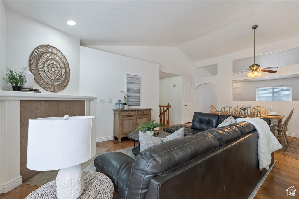 Living room with ceiling fan, baseboards, wood finished floors, and lofted ceiling