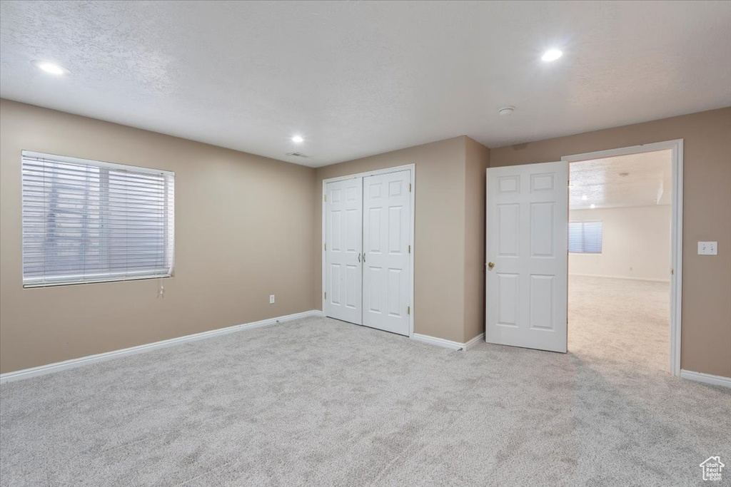 Unfurnished bedroom with light carpet, baseboards, and recessed lighting