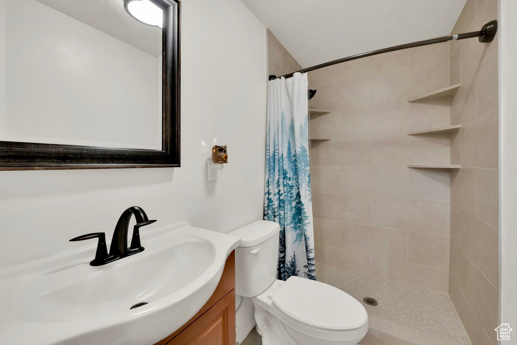 Full bath featuring toilet, a tile shower, and vanity
