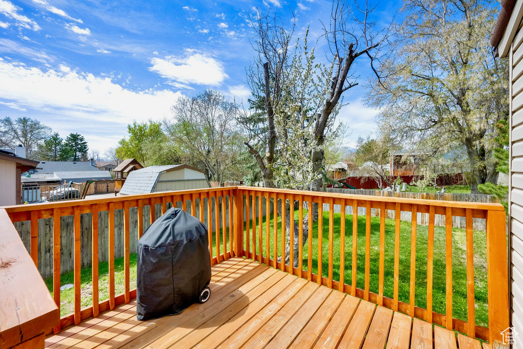 Wooden terrace with a grill, a yard, fence, and a residential view