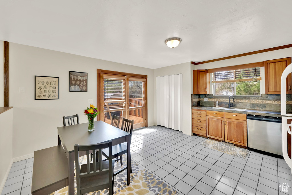 Kitchen with light tile patterned floors, dishwasher, a sink, brown cabinets, and backsplash
