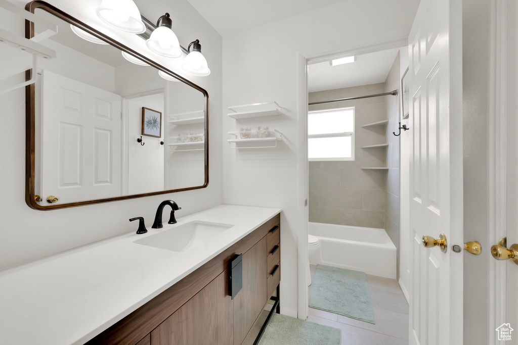 Full bathroom with toilet, tile patterned floors, vanity, and shower / bath combination