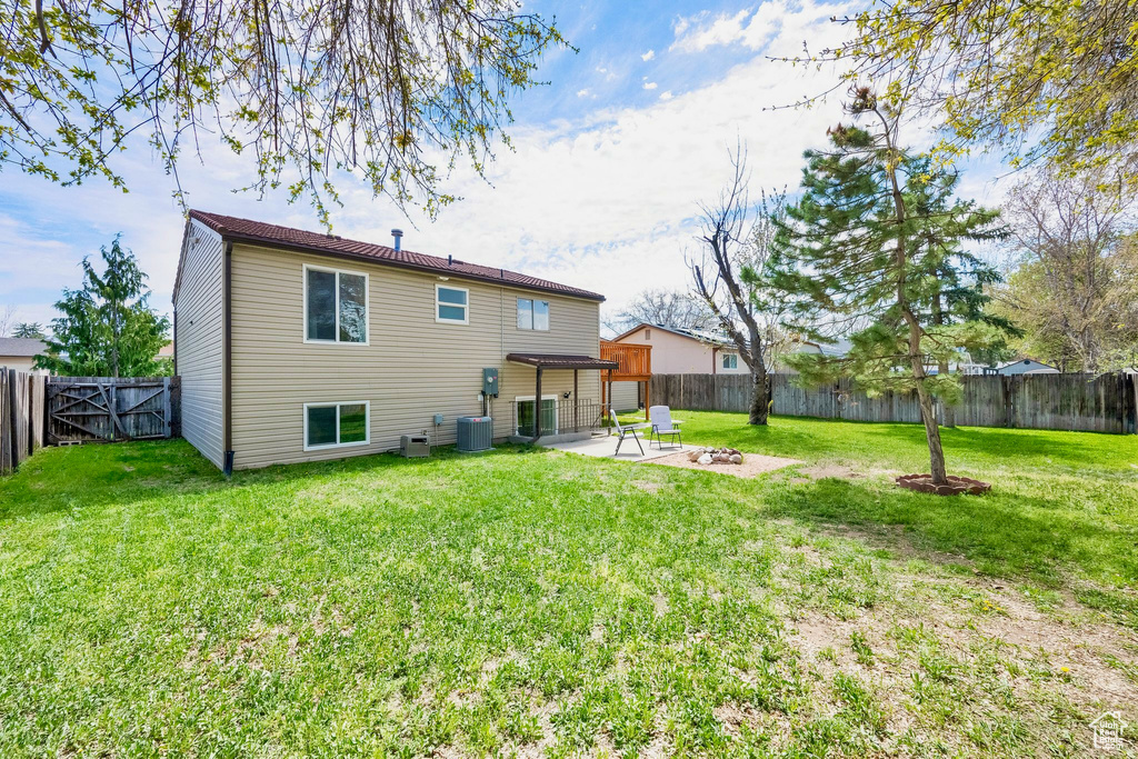 Back of house featuring a patio, a fenced backyard, a lawn, and central AC