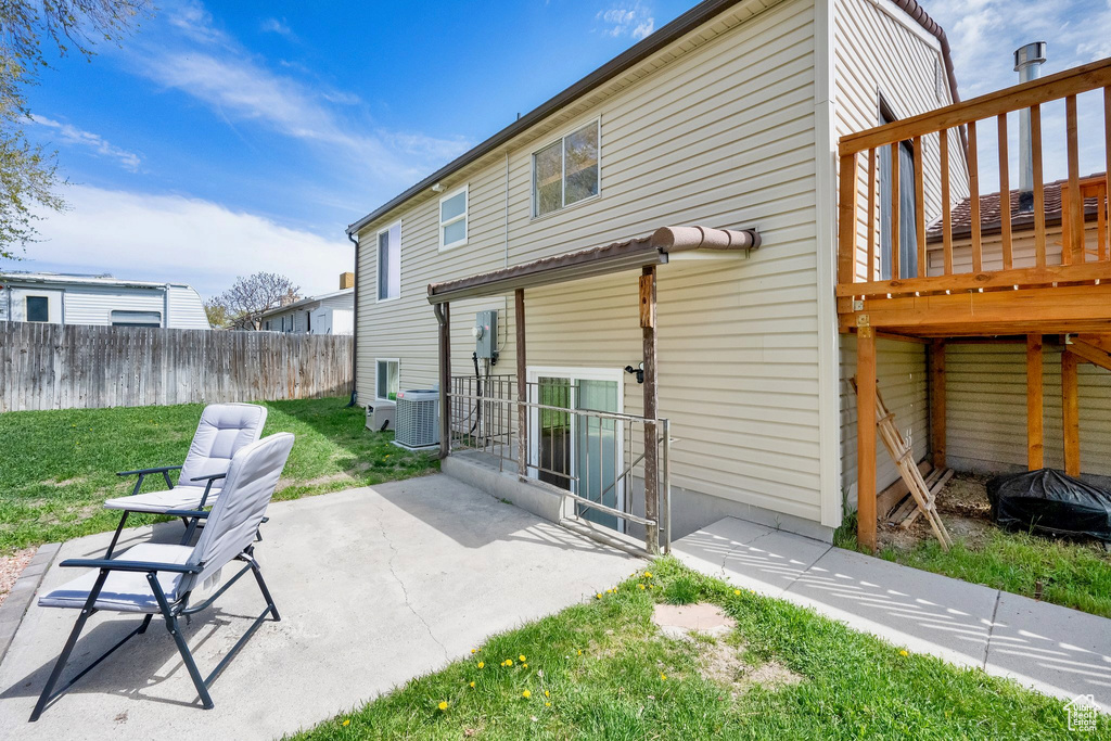 Rear view of house featuring a yard, a patio, central AC, and fence
