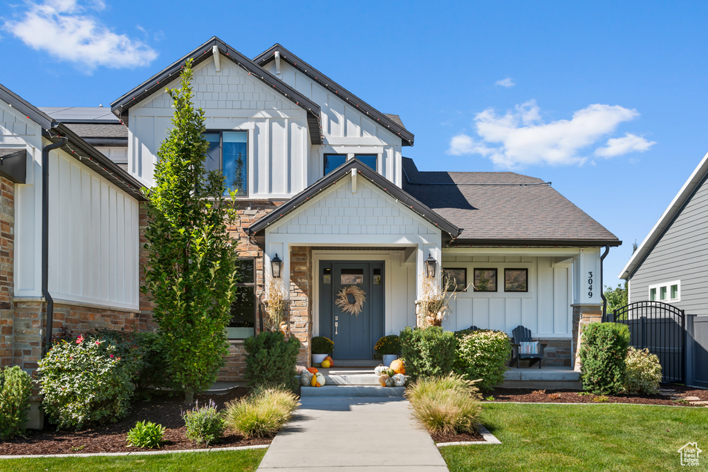 View of front of house featuring board and batten siding, a front lawn, a gate, and roof with shingles