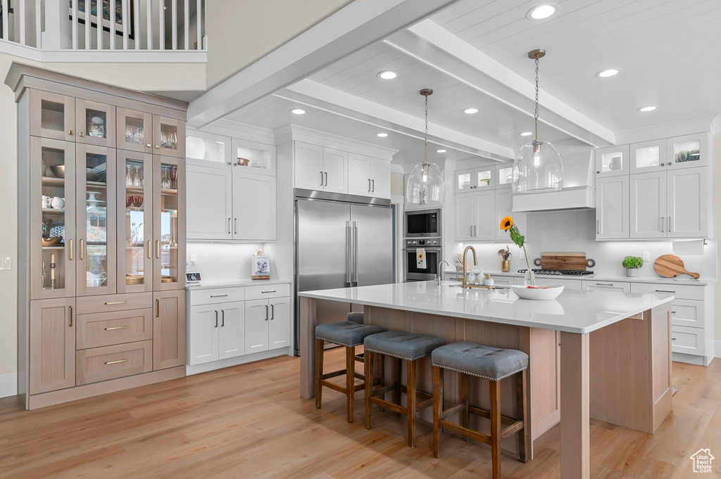 Kitchen with a sink, beam ceiling, light wood-type flooring, and built in appliances