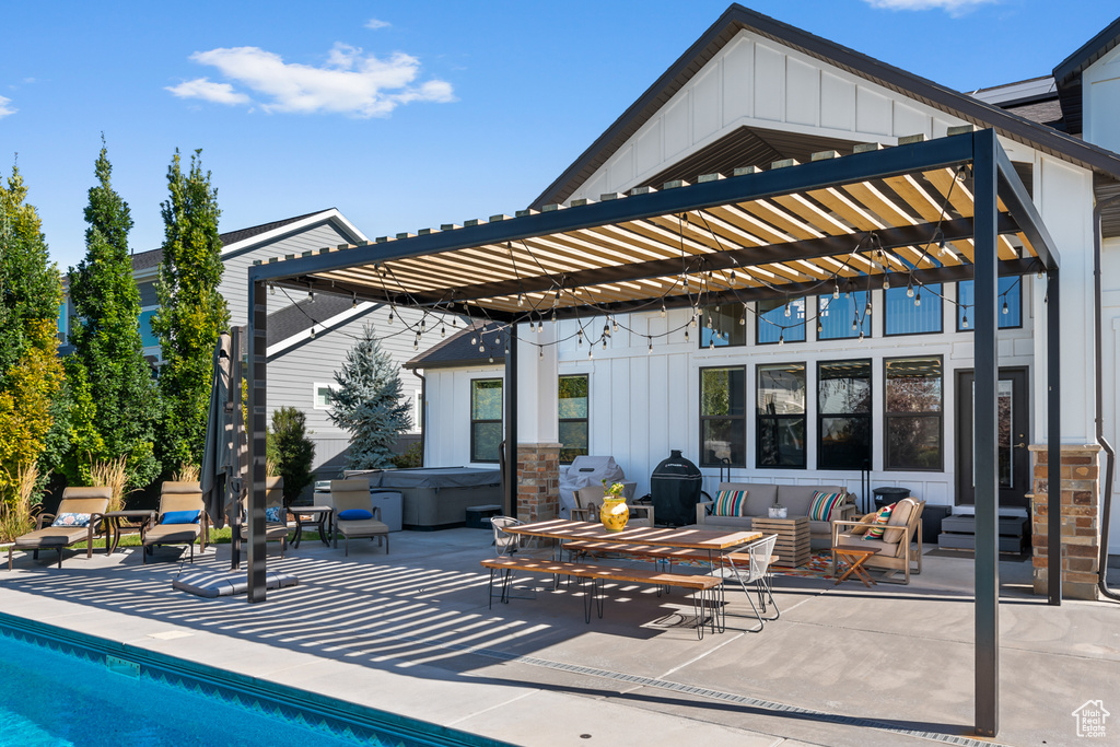 Rear view of house with board and batten siding, a pergola, a patio, and a hot tub