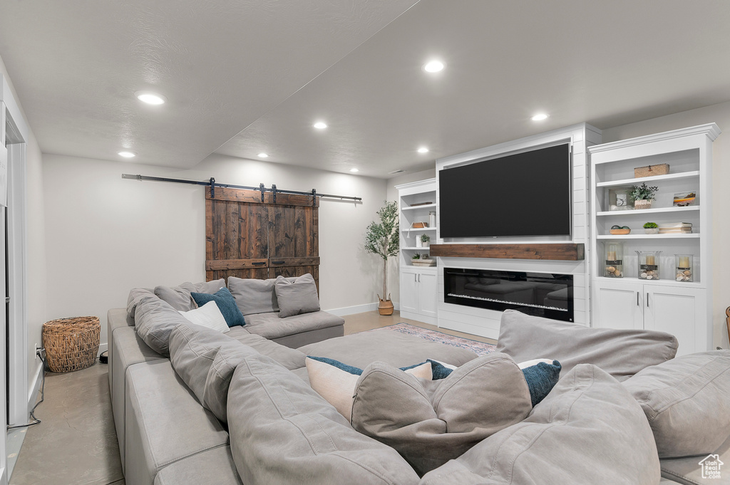 Living area with finished concrete flooring, recessed lighting, baseboards, and a barn door