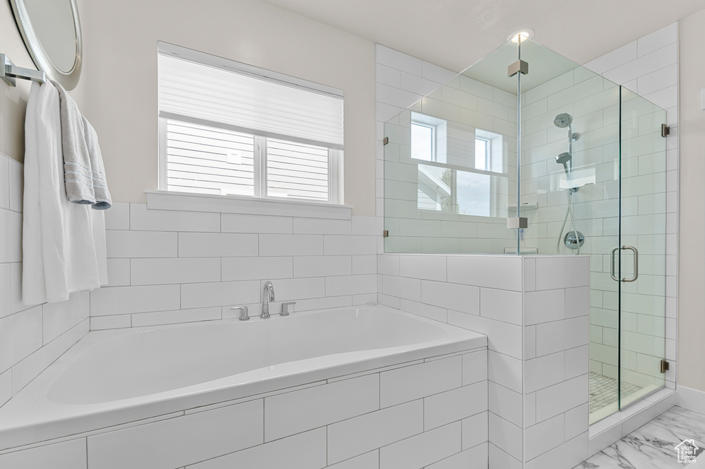 Bathroom with a wealth of natural light, marble finish floor, a stall shower, and a garden tub