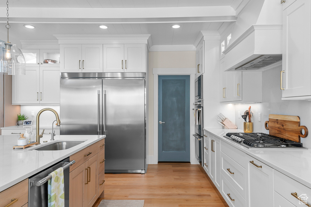 Kitchen featuring custom range hood, recessed lighting, light countertops, appliances with stainless steel finishes, and a sink