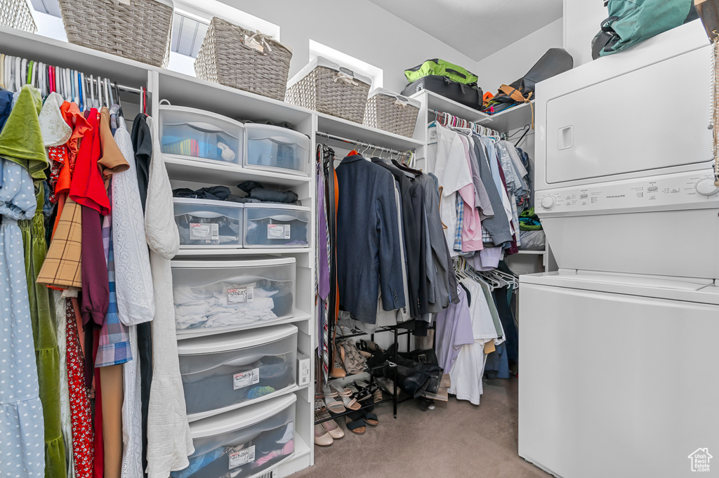 Walk in closet featuring stacked washer / dryer and carpet flooring