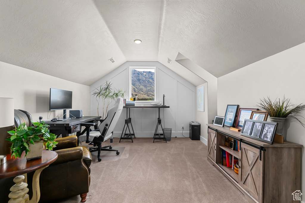Office featuring visible vents, baseboards, a textured ceiling, light colored carpet, and lofted ceiling