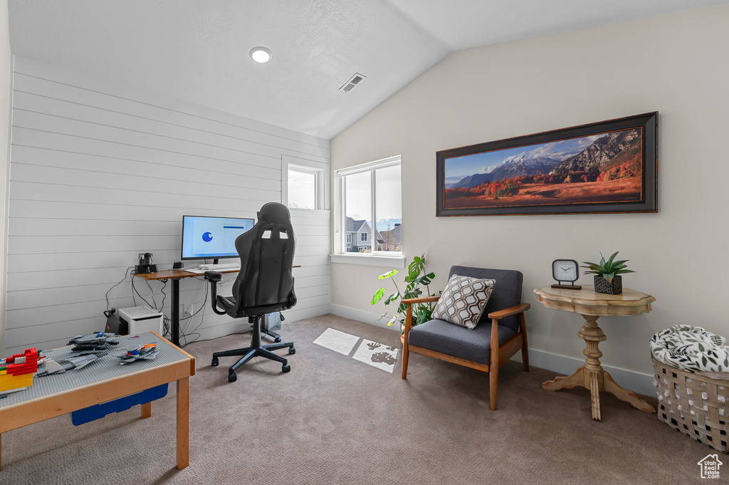 Carpeted office space featuring visible vents, baseboards, and lofted ceiling
