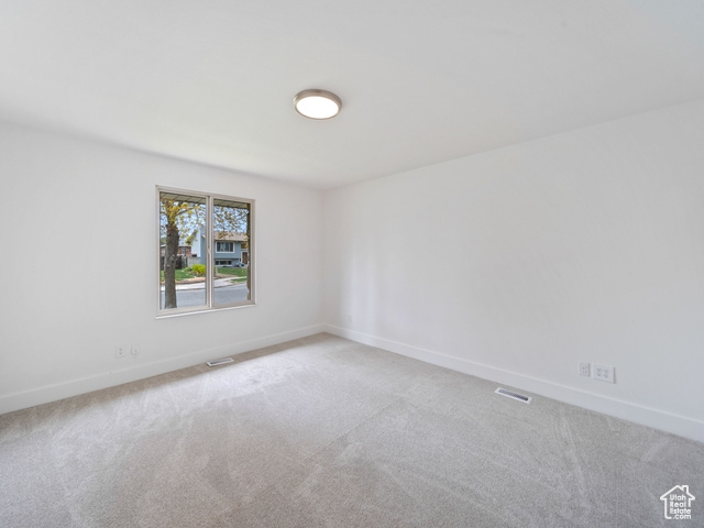 Unfurnished room featuring carpet floors, visible vents, and baseboards