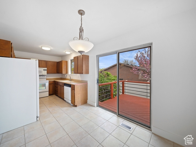 Kitchen featuring hanging light fixtures, light tile patterned flooring, white appliances, light countertops, and visible vents