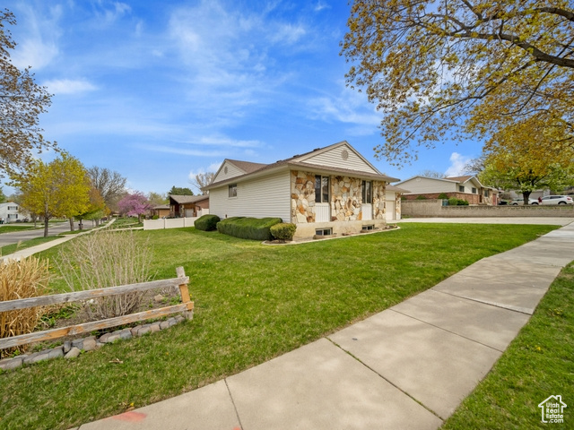 View of front facade with stone siding, fence, a front yard, and a garage