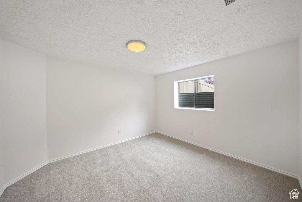 Carpeted spare room with baseboards and a textured ceiling
