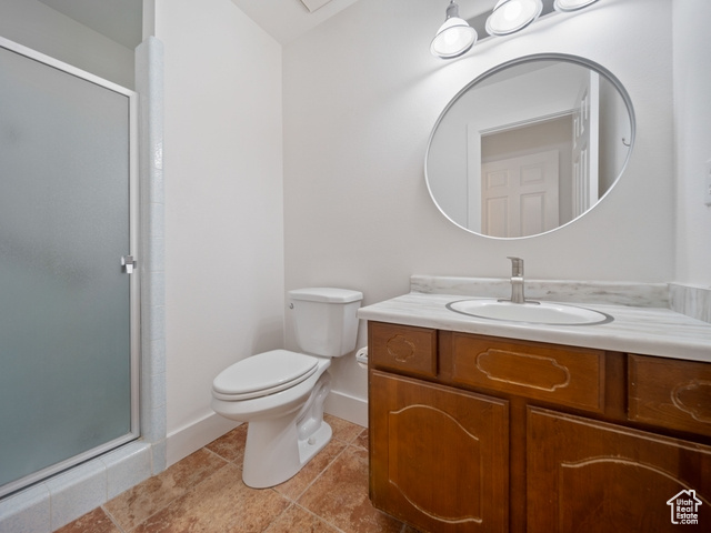 Bathroom with tile patterned floors, toilet, a stall shower, baseboards, and vanity