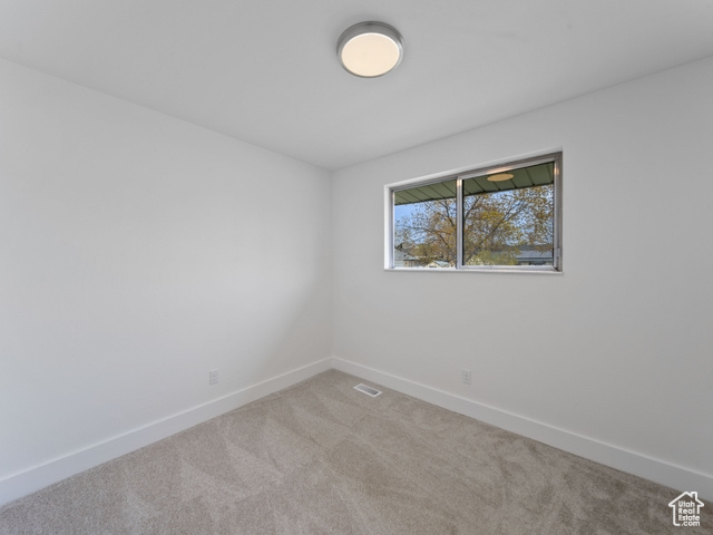 Carpeted spare room with baseboards and visible vents