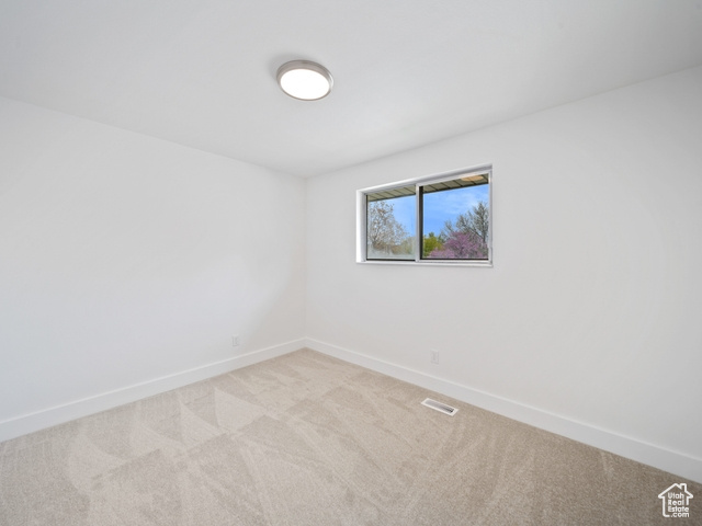 Carpeted spare room featuring visible vents and baseboards