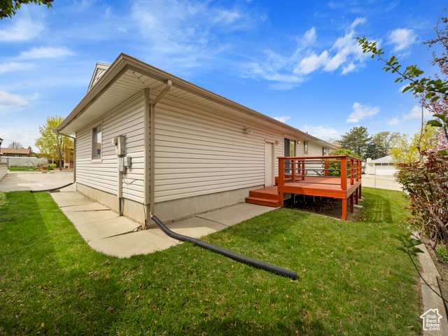 Back of house with a wooden deck and a yard