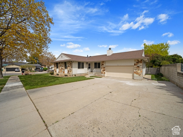 Single story home with a garage, concrete driveway, a chimney, fence, and a front yard