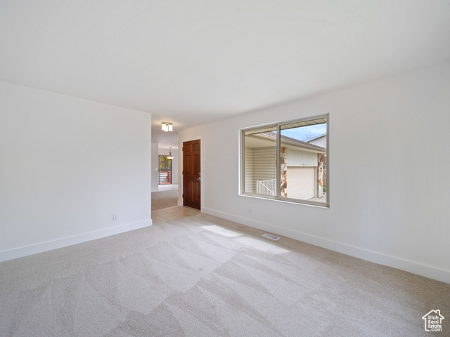Unfurnished room with light colored carpet, a wealth of natural light, visible vents, and baseboards