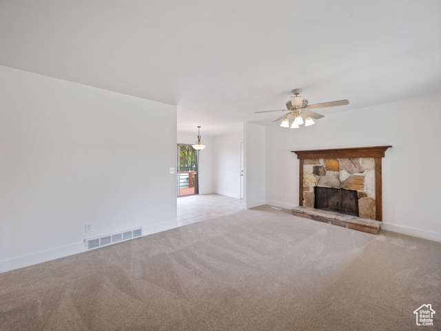 Unfurnished living room with light carpet, baseboards, visible vents, ceiling fan, and a fireplace