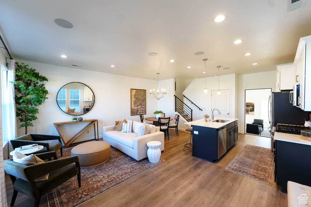 Living room featuring a wealth of natural light, a notable chandelier, light wood-style flooring, and recessed lighting