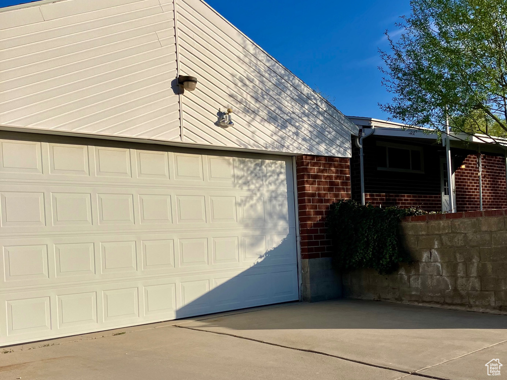 View of side of property with concrete driveway, a garage, and brick siding