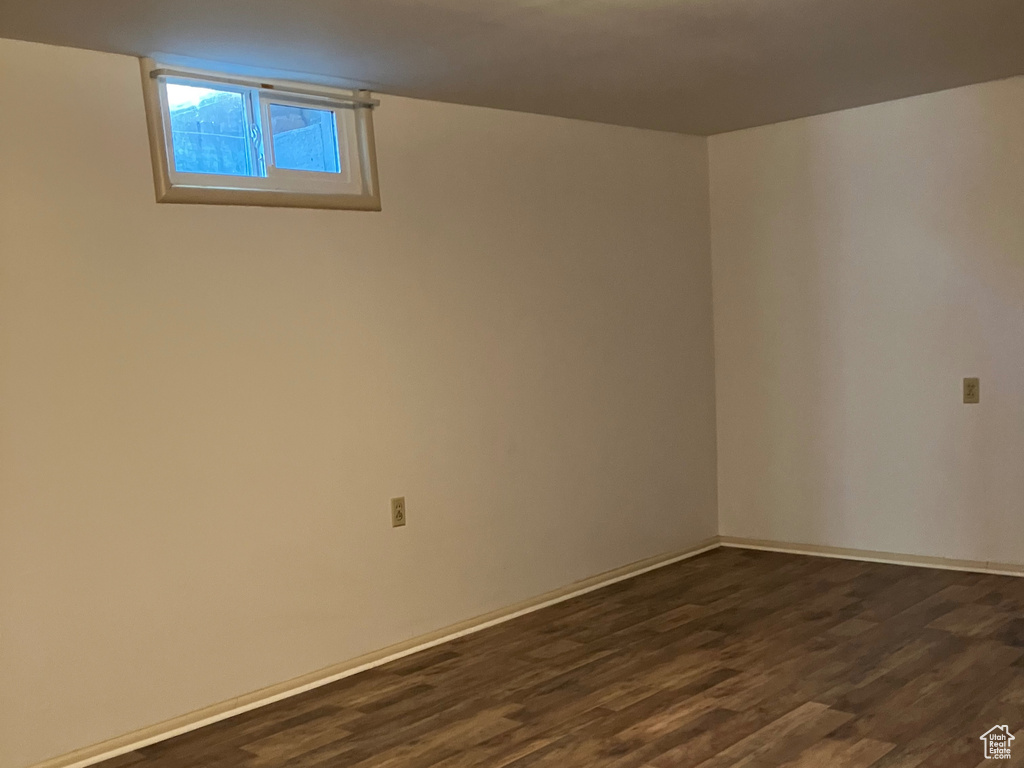 Empty room featuring dark wood-type flooring and baseboards