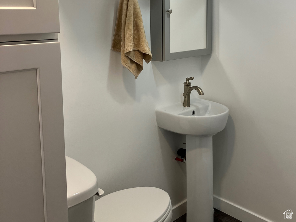Bathroom featuring toilet, wood finished floors, and baseboards