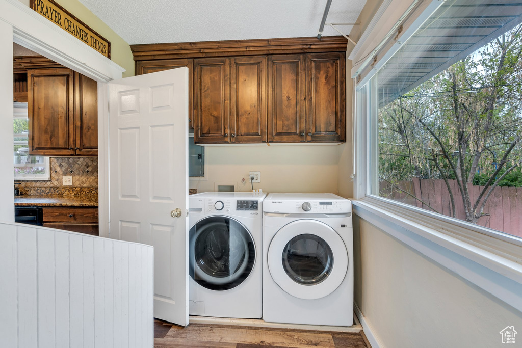 Clothes washing area with cabinet space, independent washer and dryer, and wood finished floors