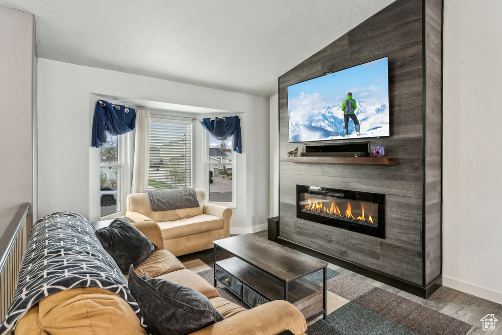 Living area featuring lofted ceiling, baseboards, wood finished floors, and a glass covered fireplace