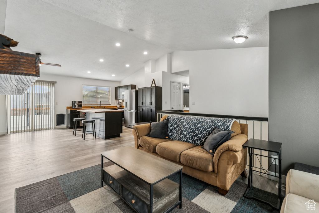 Living area with lofted ceiling, light wood finished floors, recessed lighting, and ceiling fan