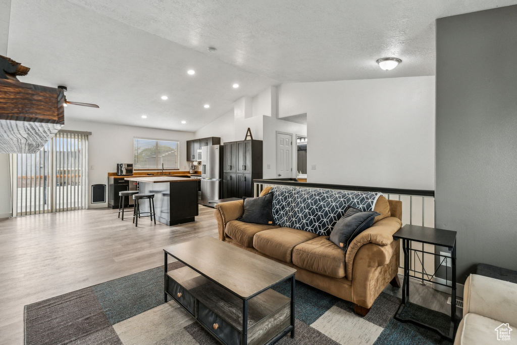 Living room with recessed lighting, vaulted ceiling, ceiling fan, and light wood-type flooring