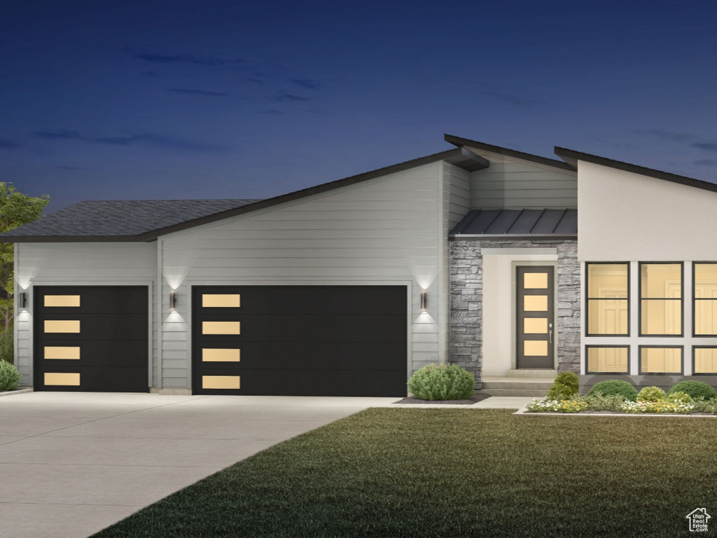 Modern home with a garage, driveway, stone siding, metal roof, and a standing seam roof