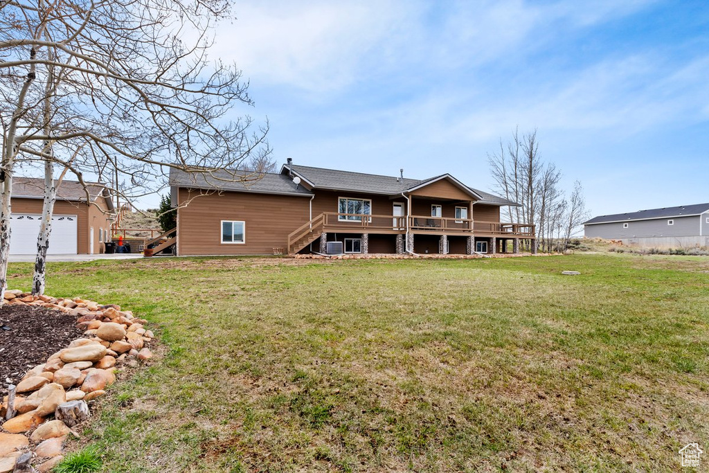 Rear view of property with a lawn, a deck, and stairs
