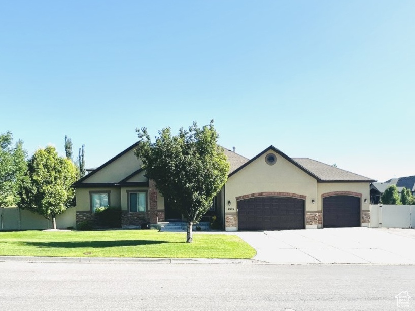 View of front of home with a garage, driveway, stucco siding, a residential view, and stone siding