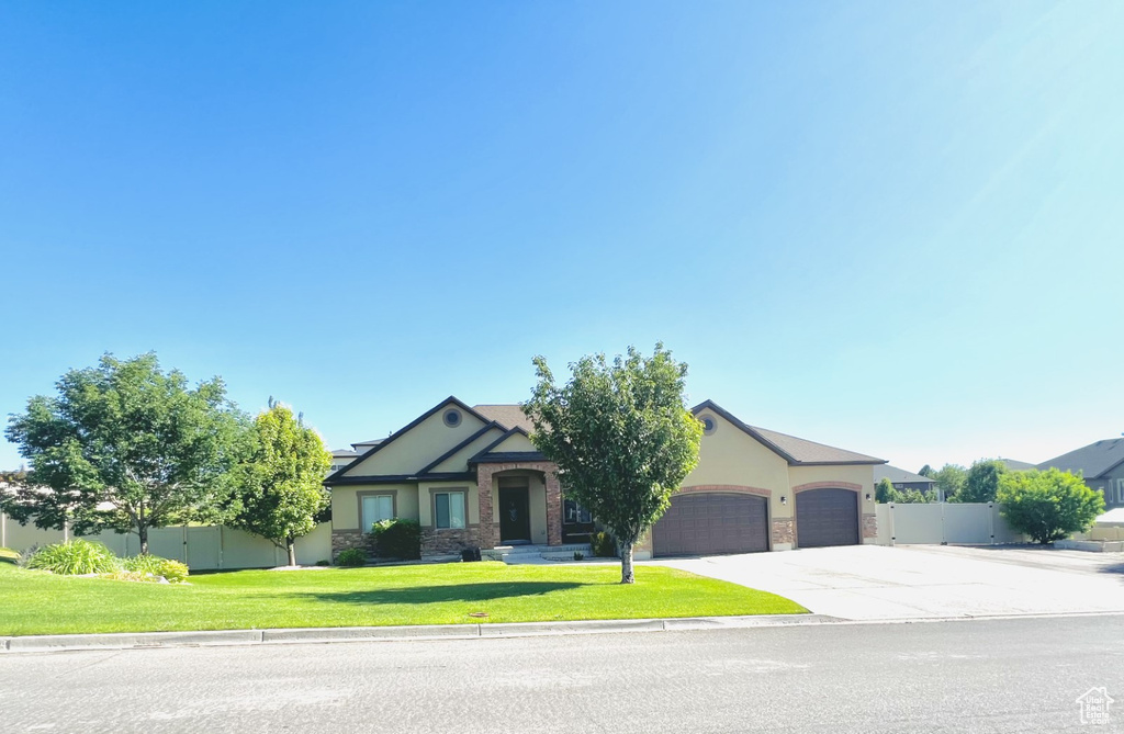 View of front of property with a garage, driveway, stucco siding, and stone siding