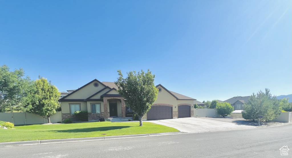 View of front of house with a garage, concrete driveway, stone siding, and stucco siding