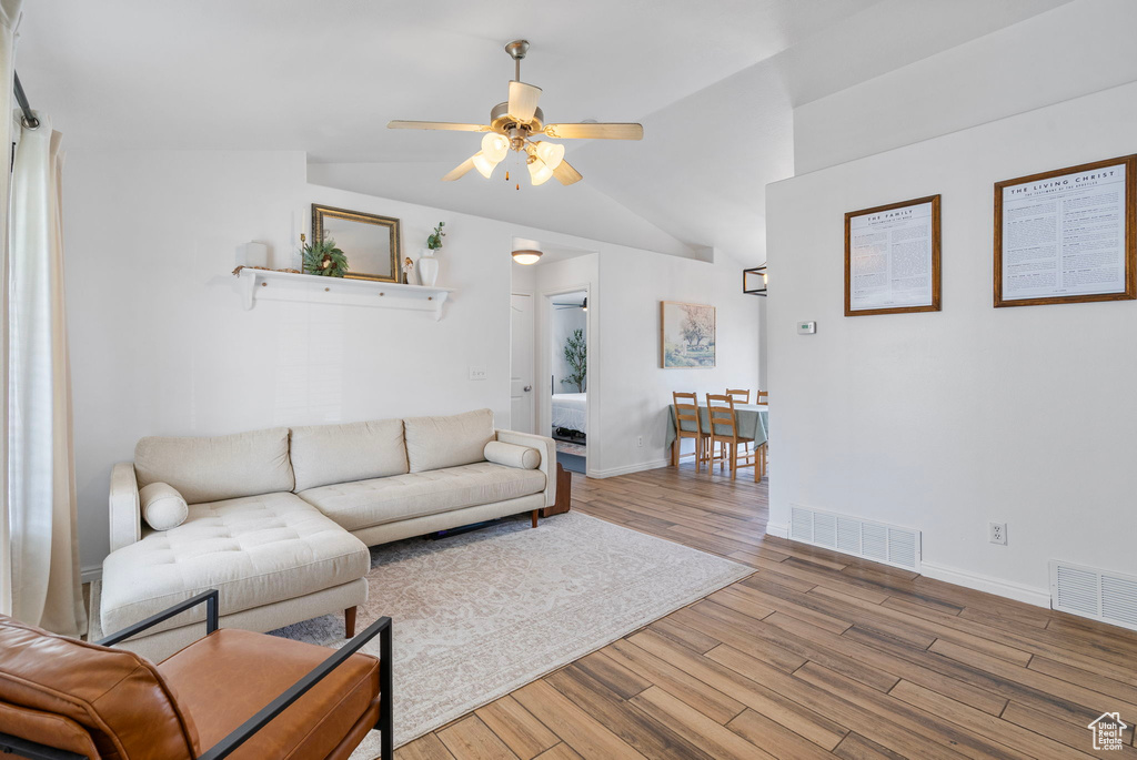 Living area with a ceiling fan, wood finished floors, and visible vents