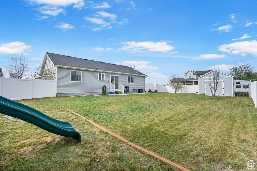 Back of property with a storage shed, a fenced backyard, entry steps, and a yard