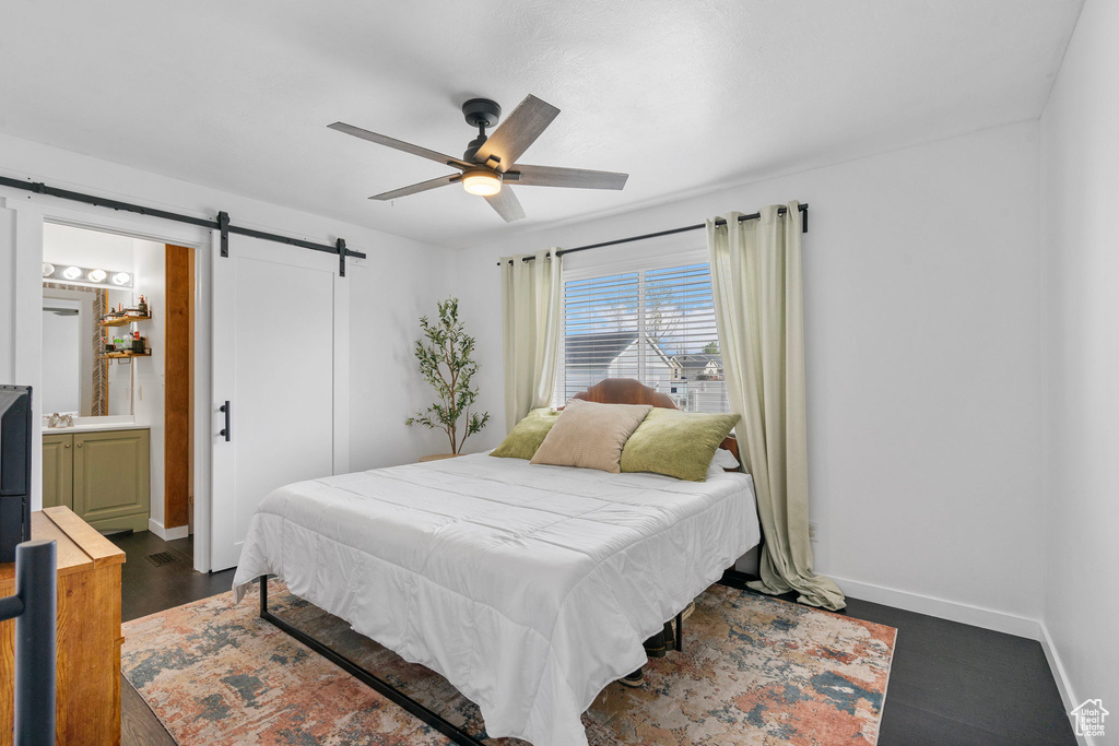 Bedroom featuring baseboards, connected bathroom, ceiling fan, and a barn door