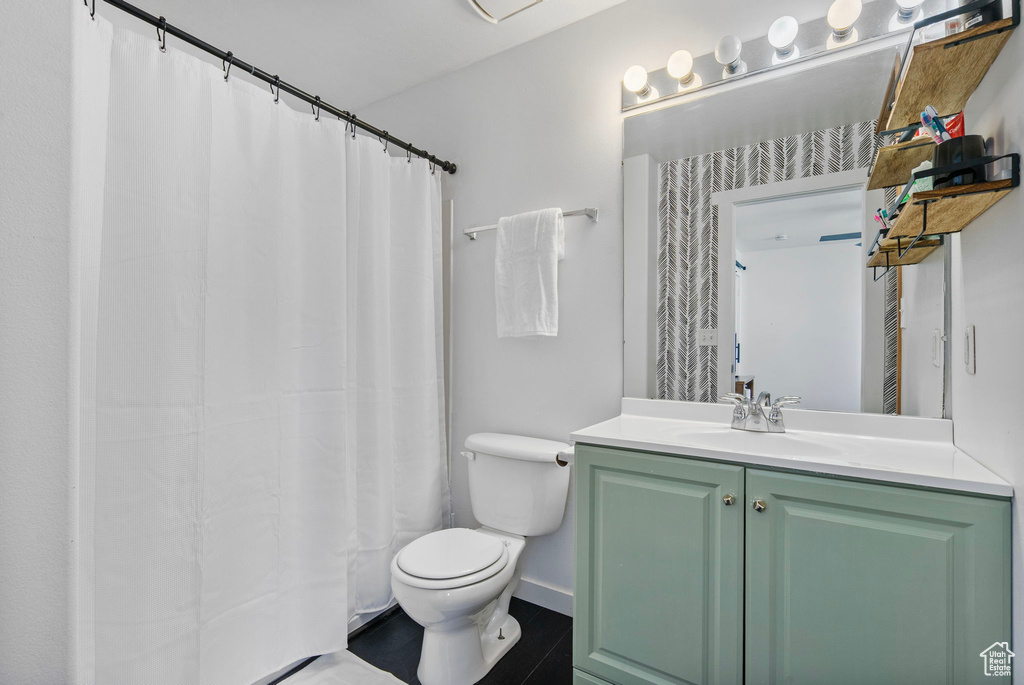 Bathroom with vanity, a shower with shower curtain, and toilet